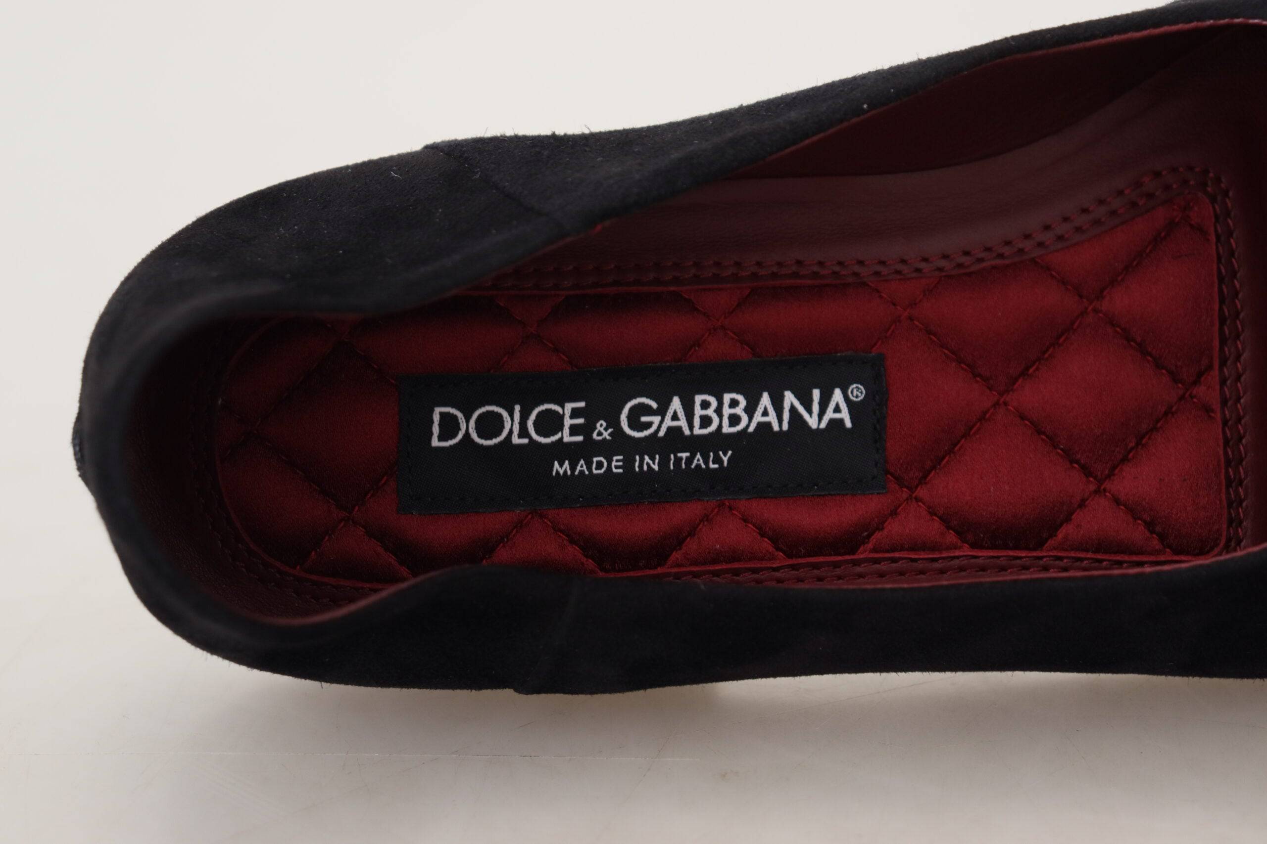 Chaussures loafers Dolce & Gabbana en suède noir avec croix dorée, style slip-on élégant et sophistiqué.