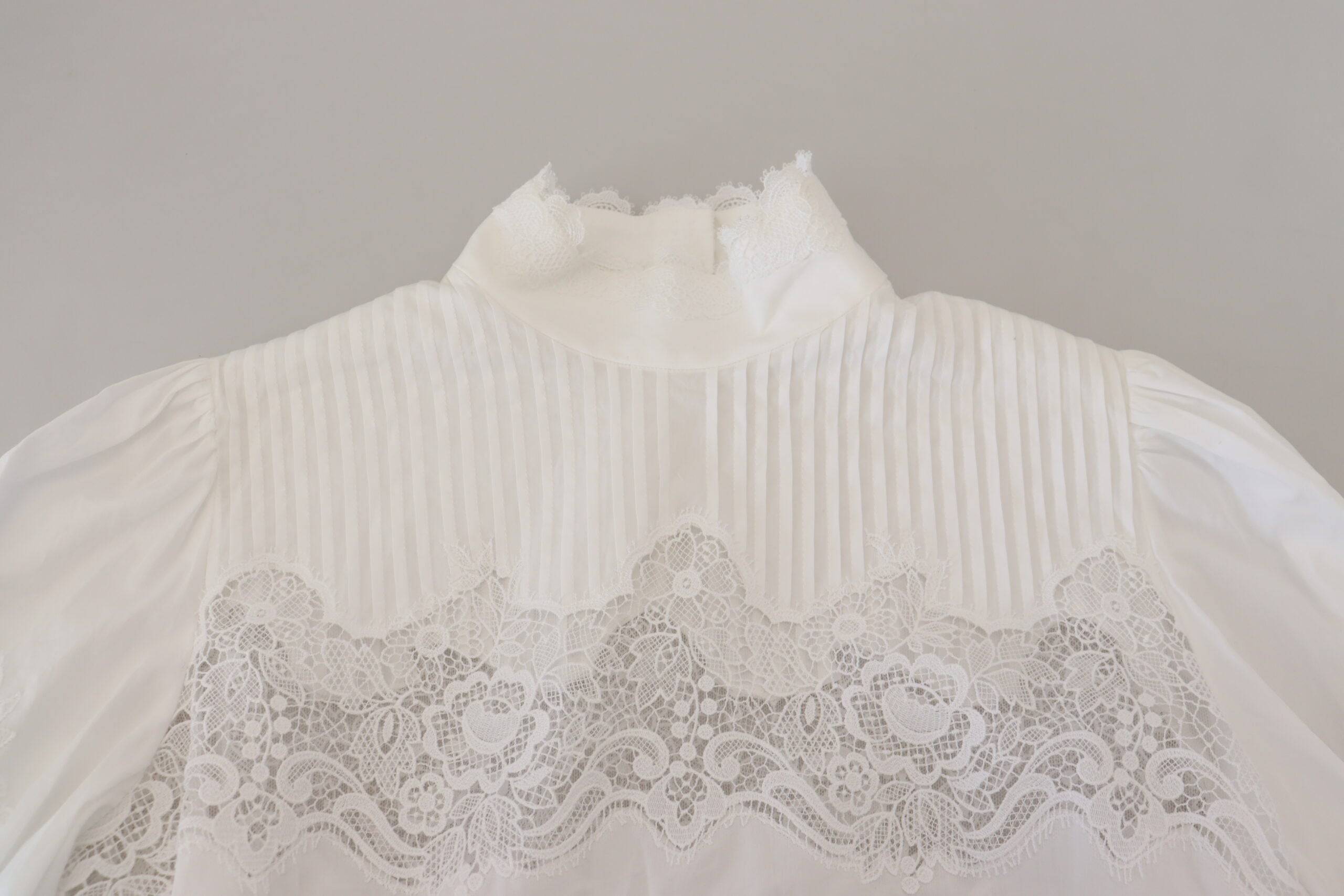 Blouse Dolce & Gabbana en coton blanc avec finition en dentelle, col roulé, vue de face.