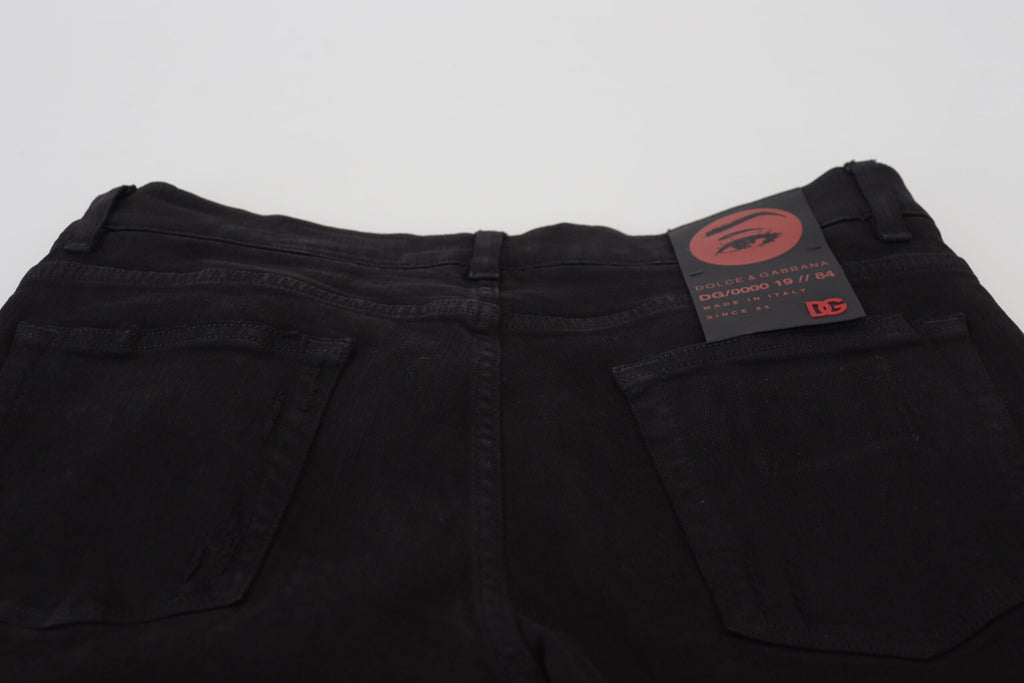 Jeans en denim noir Dolce & Gabbana coupe slim tachetés, en coton, avec un style déchiré et tendance.