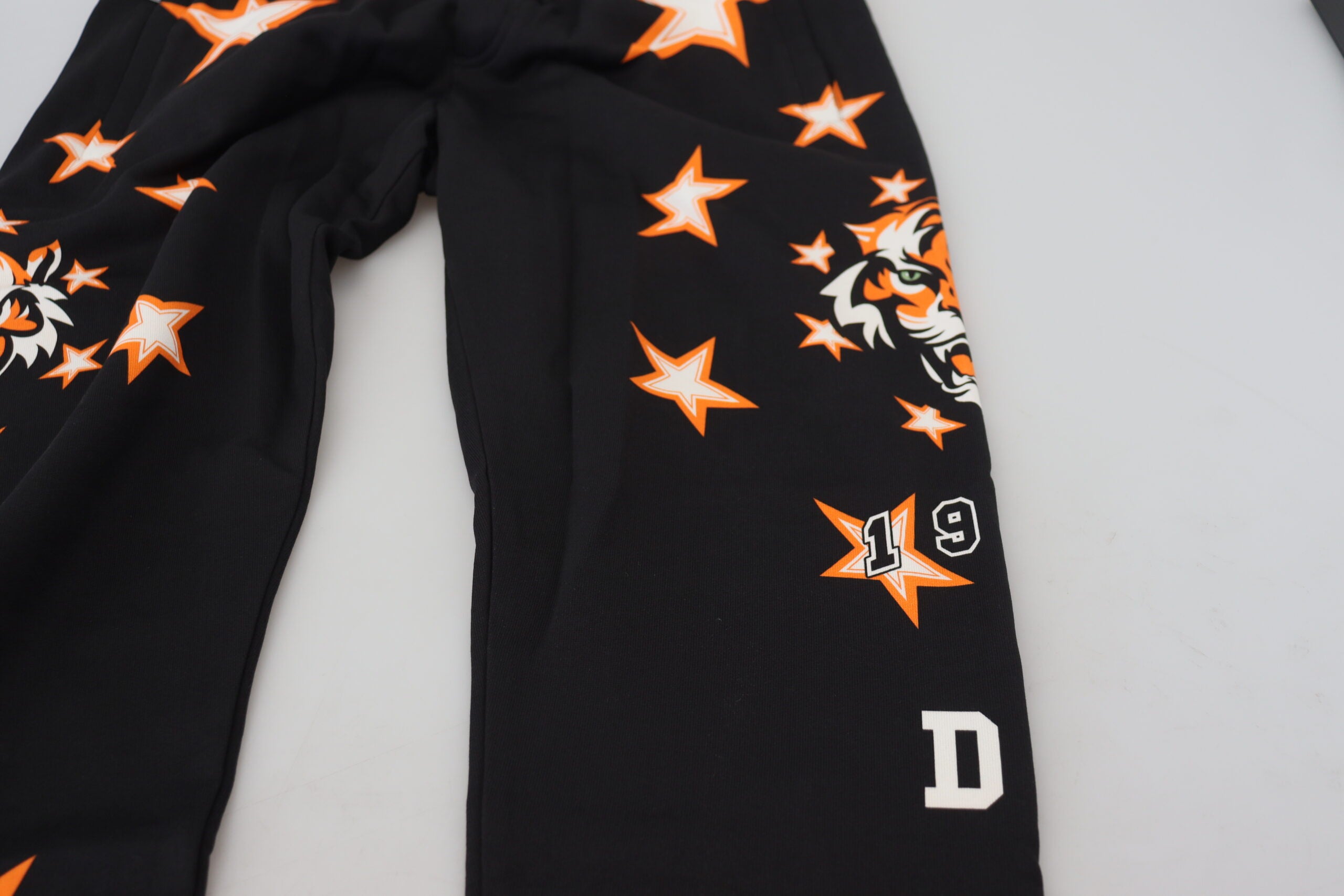 Pantalon de sport noir et orange Dolce & Gabbana avec motifs d'étoiles, tissu léger et coupe décontractée.