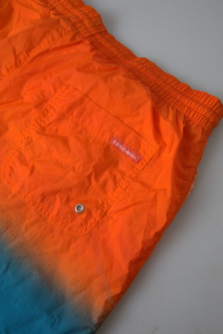 Shorts de plage Dolce & Gabbana en dégradé orange et bleu, maillot de bain léger pour homme, détails colorés et style sophistiqué.