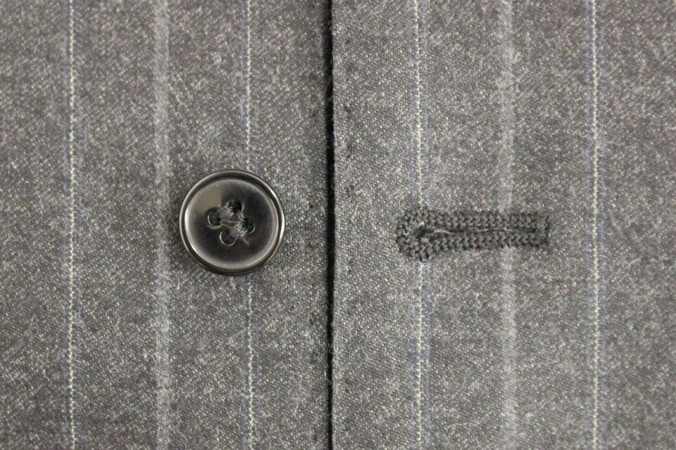 Gilet Dolce & Gabbana en laine gris rayé avec logo, porté sur un fond neutre, détail de la texture en gros plan