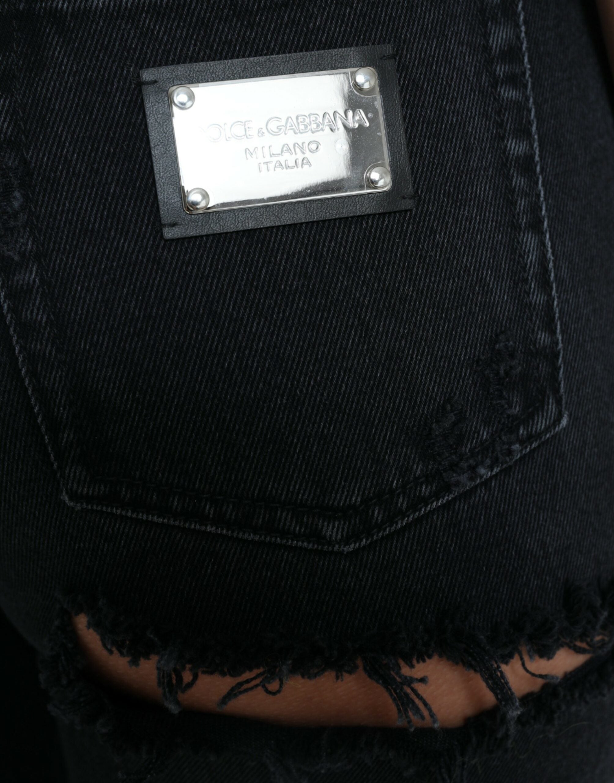 Jeans en denim noir Dolce & Gabbana, taille haute, déchirés, style décontracté, visibles en détail sur l'image.