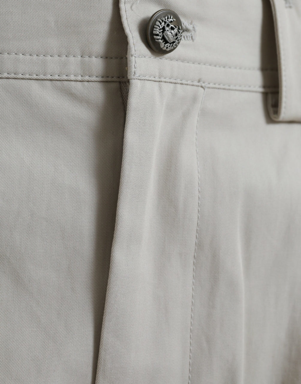 Pantalon beige en coton à taille haute et coupe tapered de Dolce & Gabbana, visible sur le modèle.