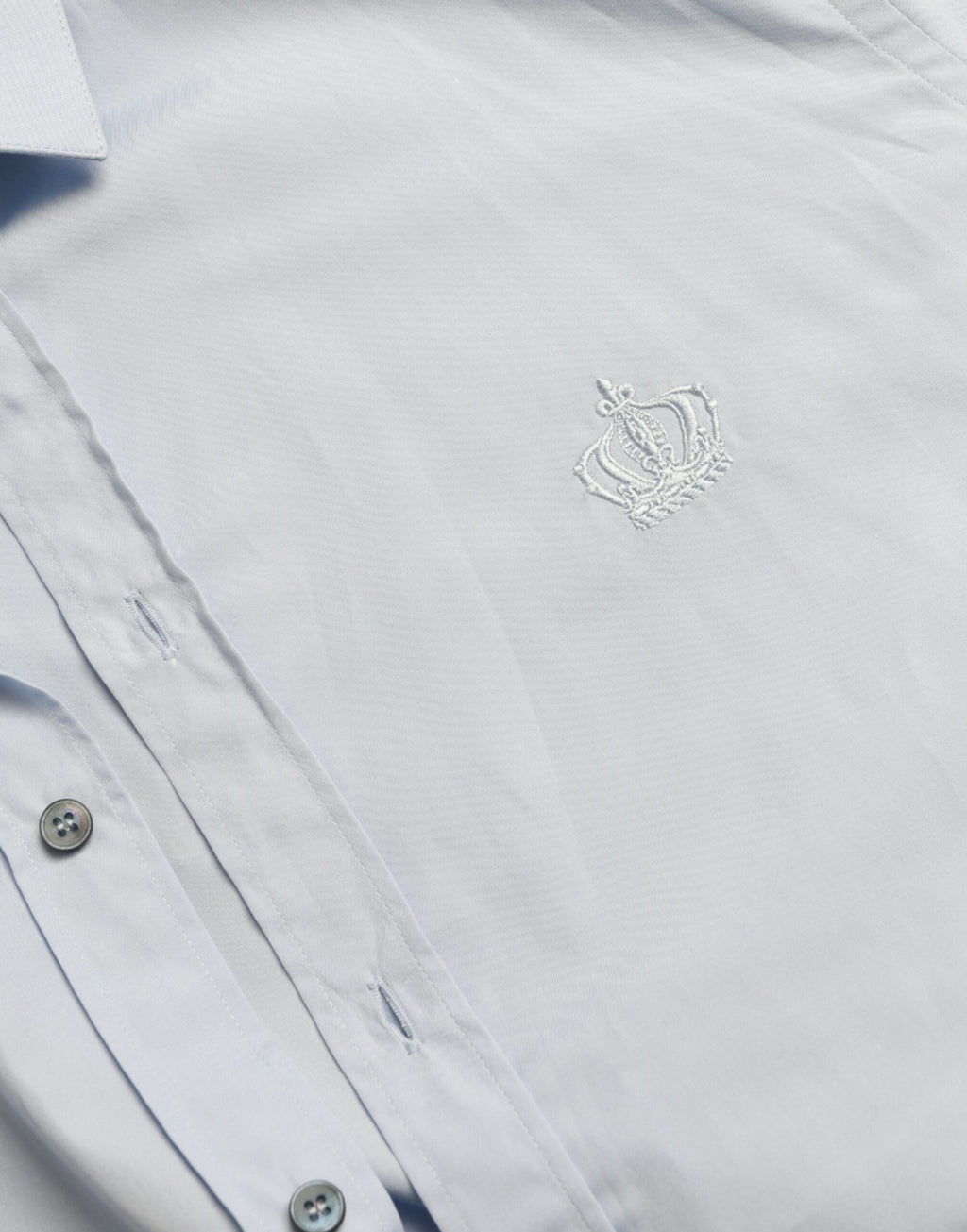 Chemise homme Dolce & Gabbana en coton bleu ciel, forme formelle avec détails dorés, style élégant et sophistiqué.
