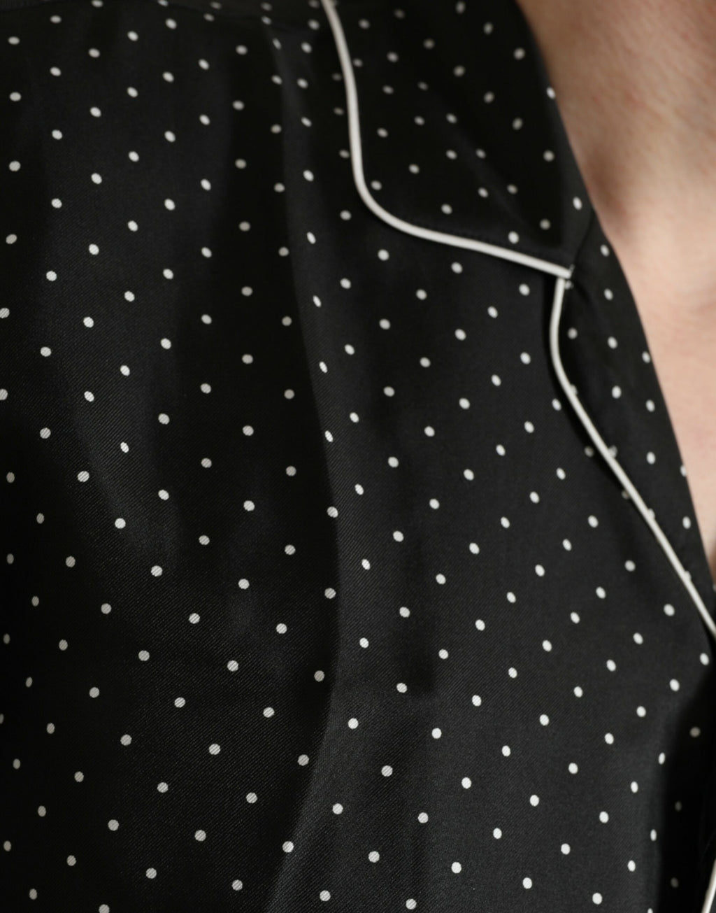 Chemise en soie noire à pois Dolce & Gabbana à manches longues, élégante et sophistiquée, visible avec motifs à pois noirs sur fond de soie.