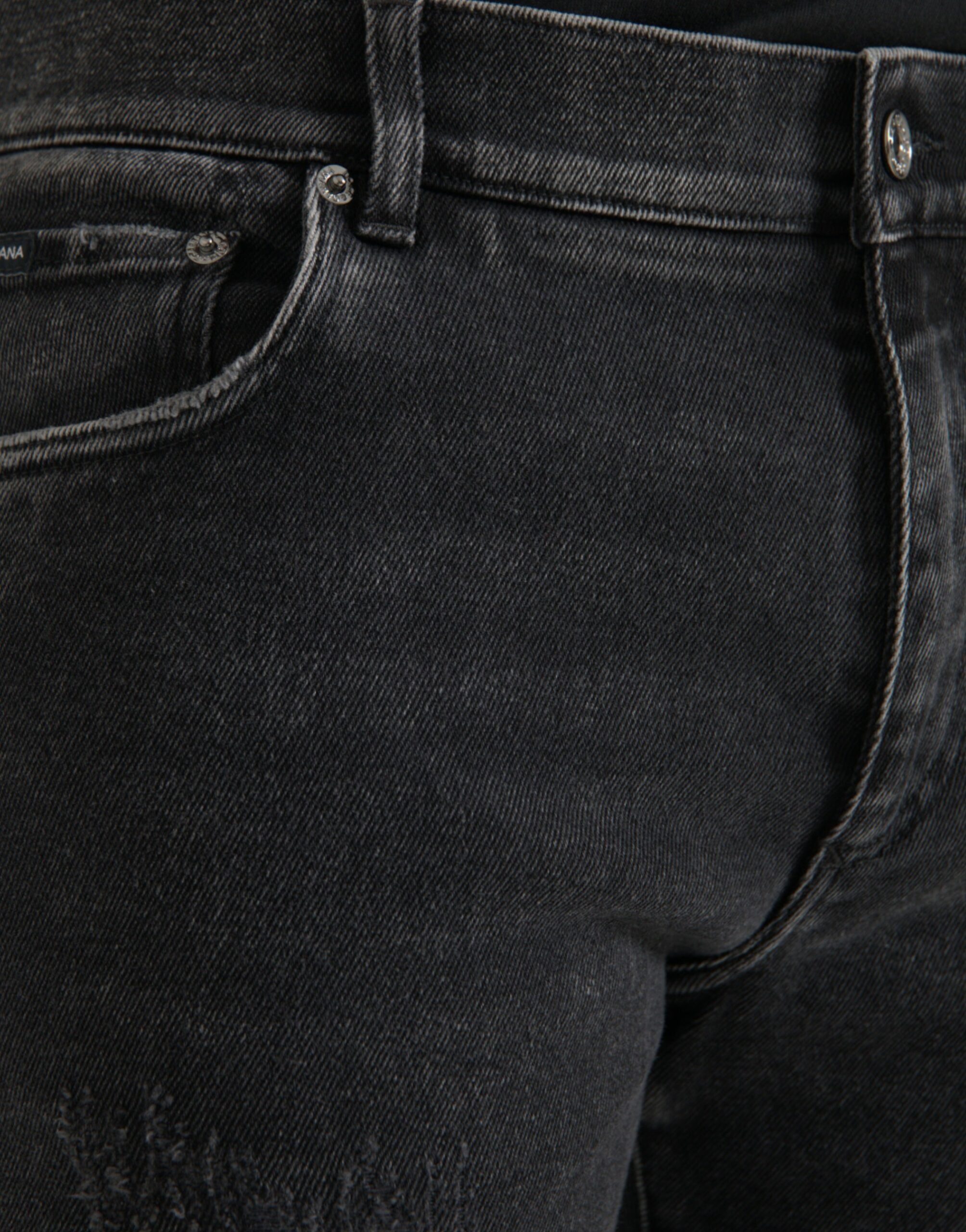 Jeans slim en denim gris Dolce & Gabbana en coton extensible avec logo, visibles sur l'image.