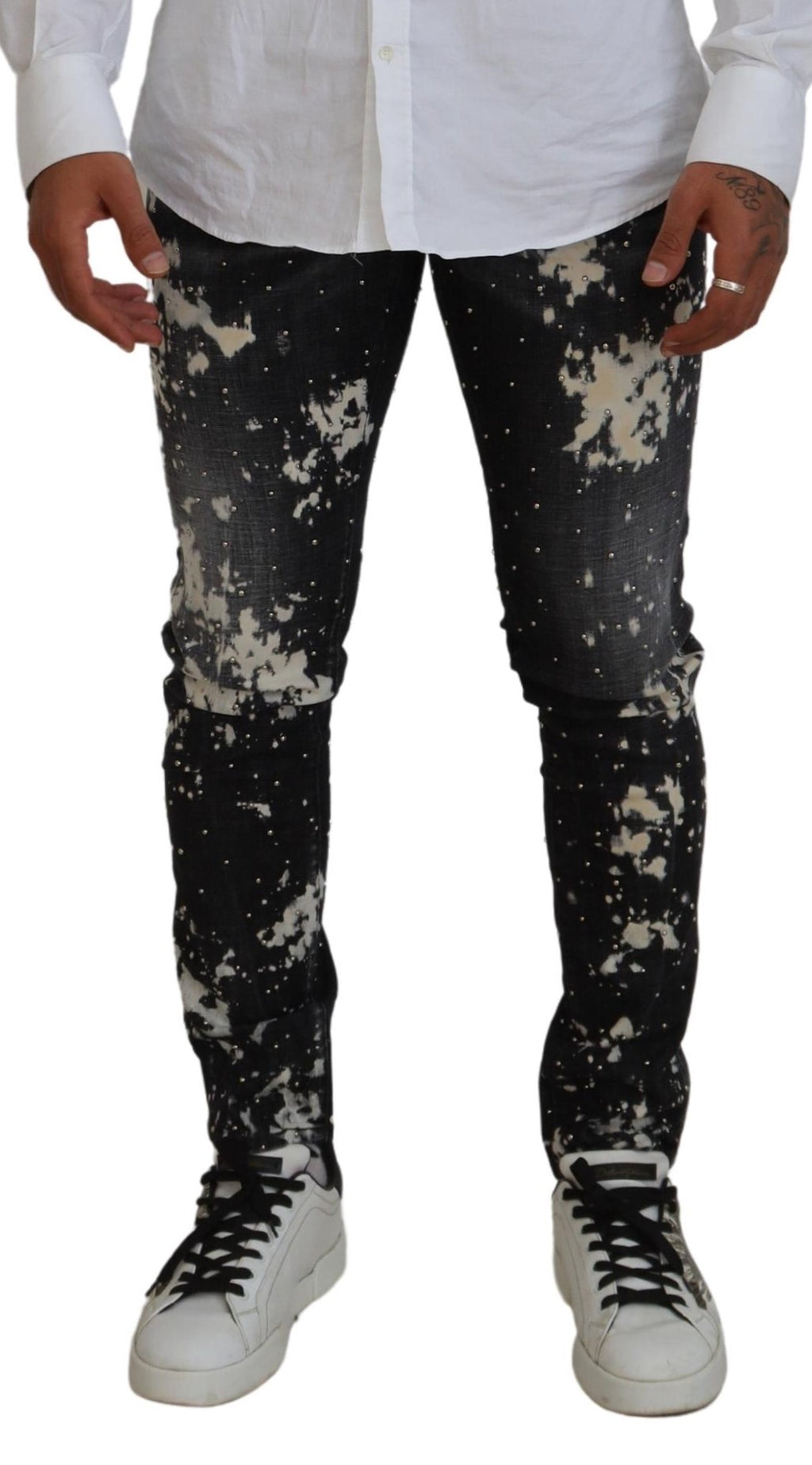 Jeans décontractés en denim noir délavé avec éclaboussures blanches, de la marque Dsquared², visibles en détail.