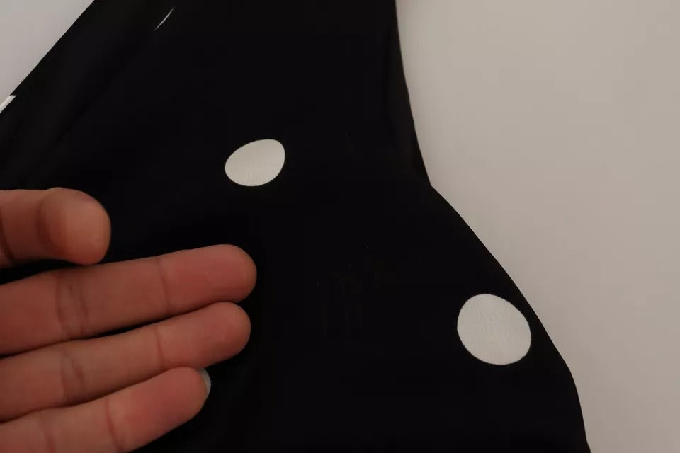 Robe midi noire en soie à pois Dolce & Gabbana avec col en V, coupe ajustée et élégante, portée par un mannequin.