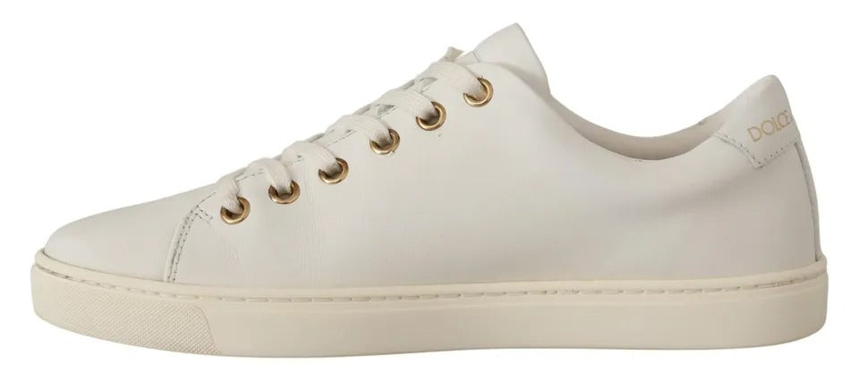 Chaussures sneakers Dolce & Gabbana en cuir blanc avec détails dorés et cœurs rouges, visibles en gros plan.
