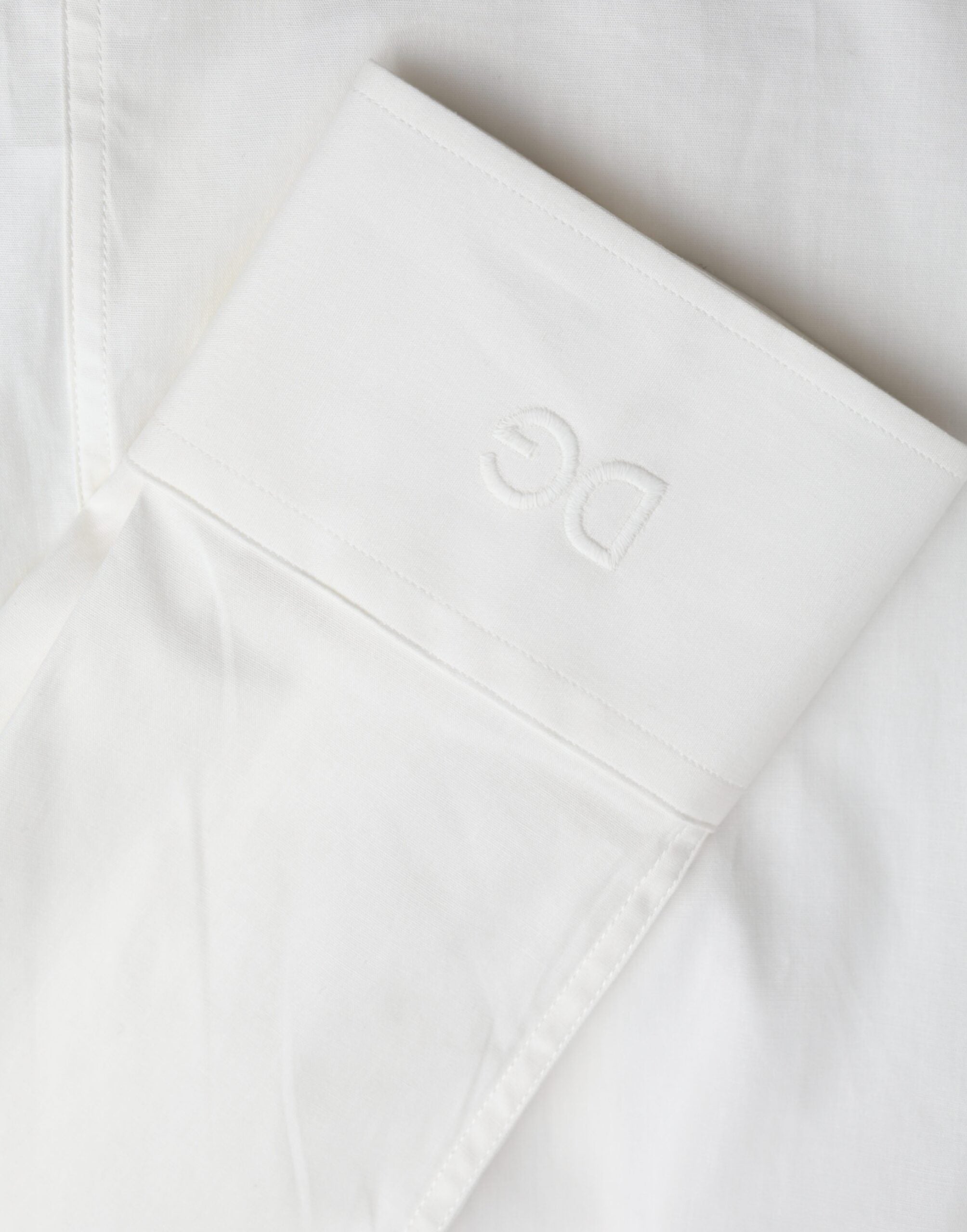 Robe blanche en coton Dolce & Gabbana avec coupe slim et chemise en or élégante, portée en style sophistiqué.