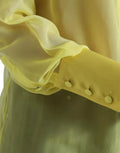 Chemisier jaune à manches longues Dolce & Gabbana avec boutons, en tissu léger et élégant.