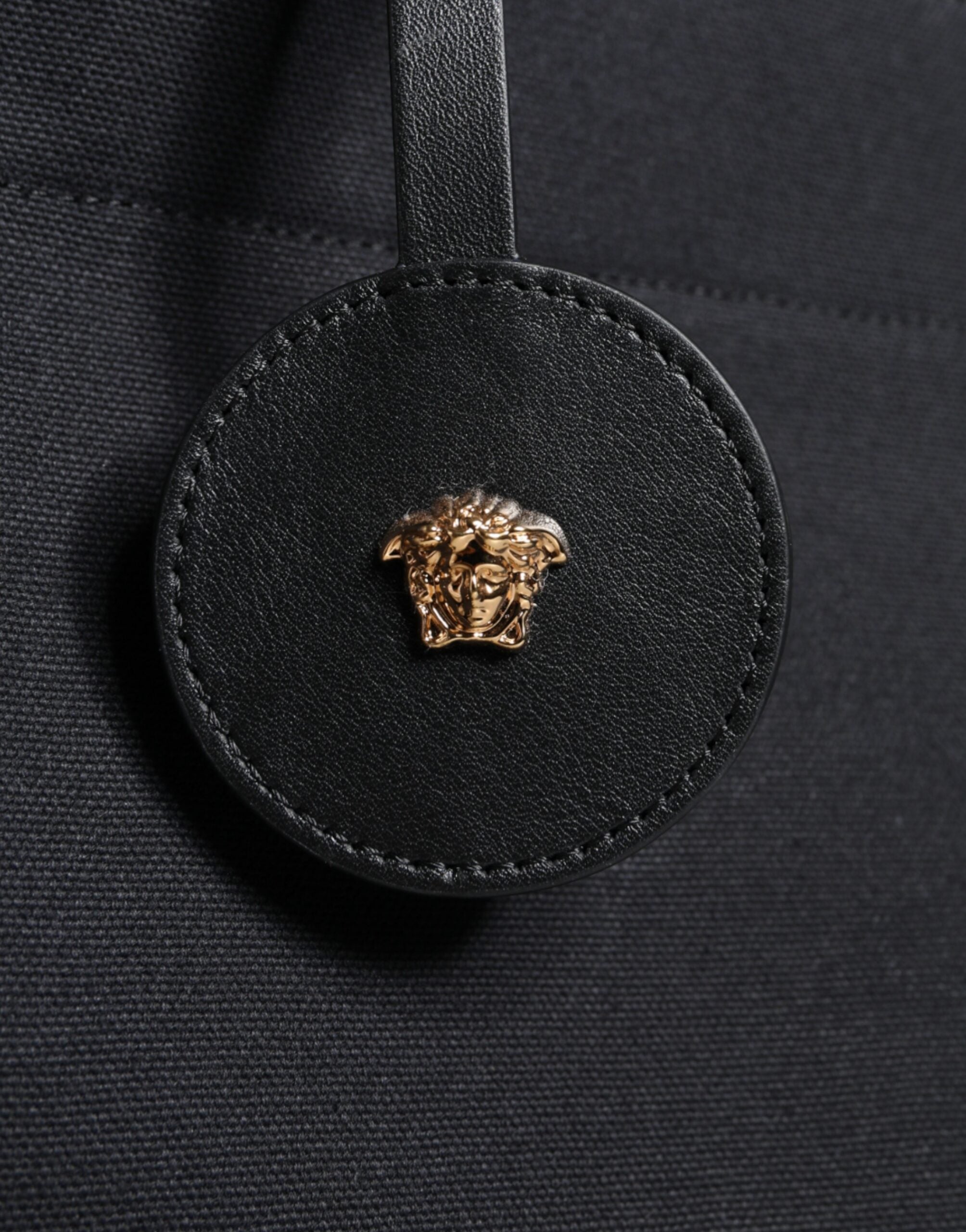 Sac à main tote à bandoulière noir Versace en toile et cuir avec logo, poignée en cuir, style élégant et pratique.
