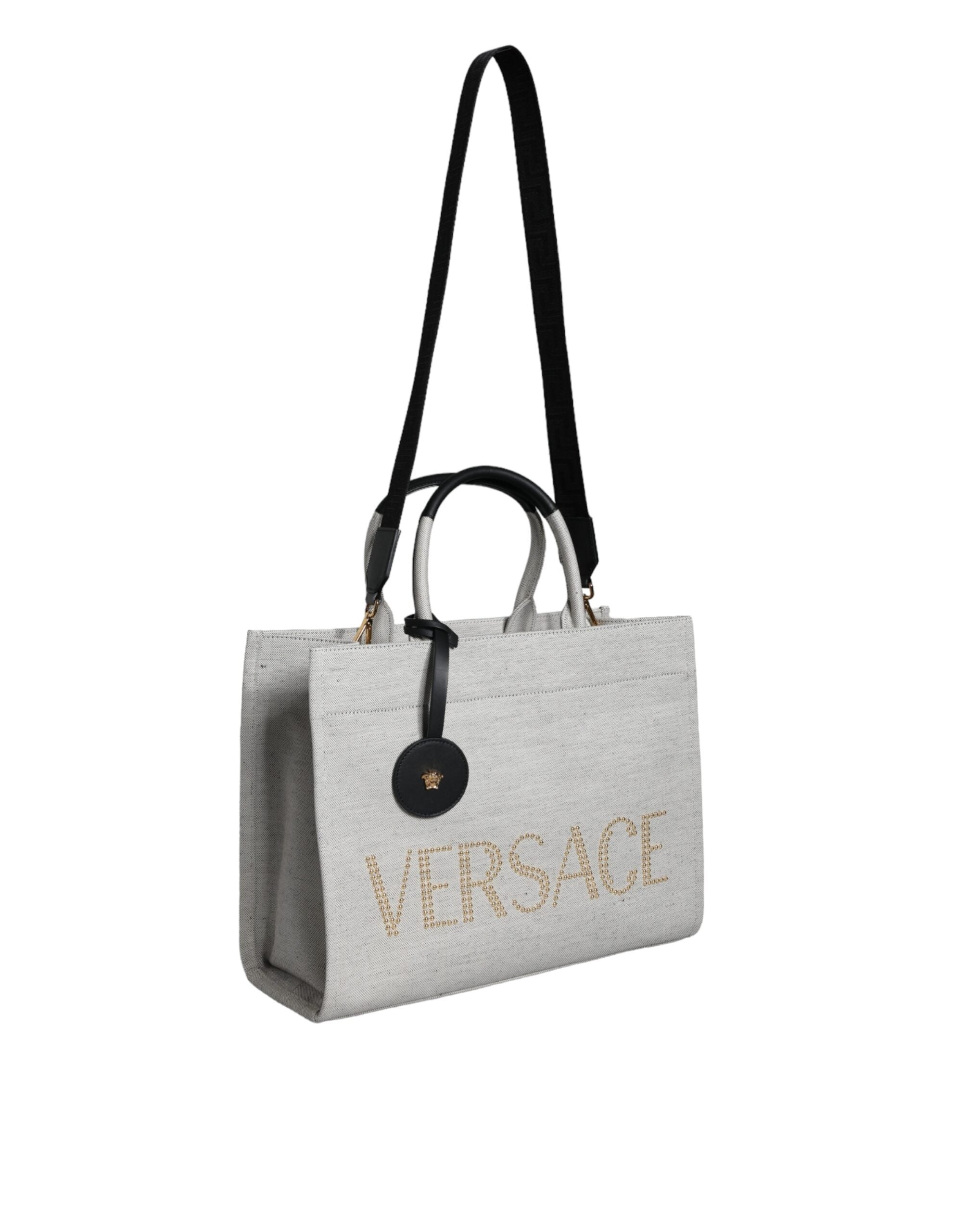 Sac cabas Versace blanc en toile et cuir avec logo, poignées torsadées et bandoulière pour un style élégant.