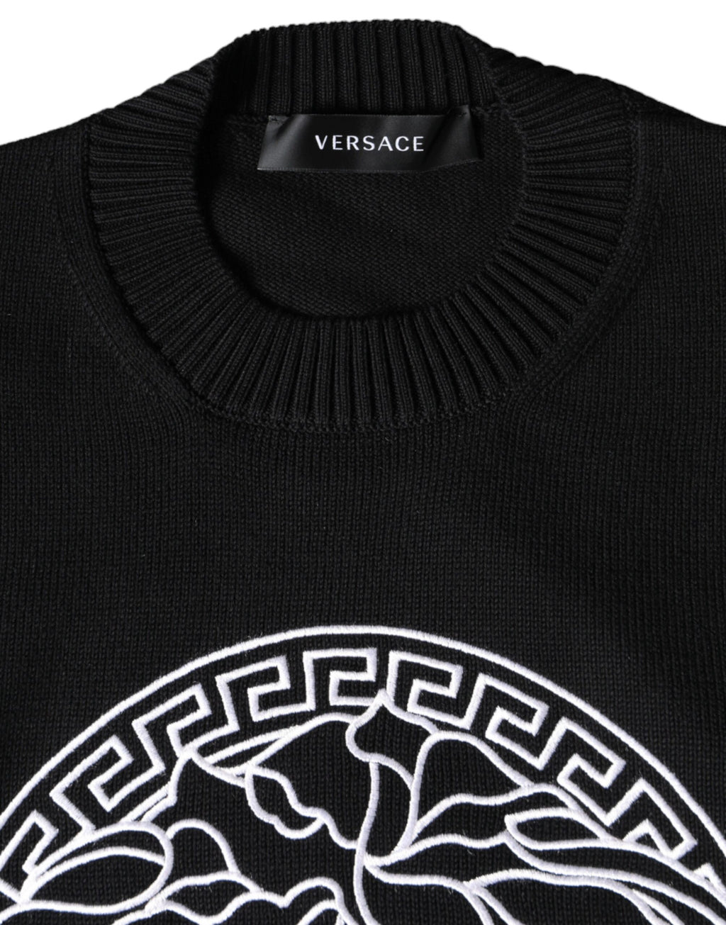 Pull-over noir Versace avec broderie Medusa, col rond et motif emblématique, en tissu doux et élégant.