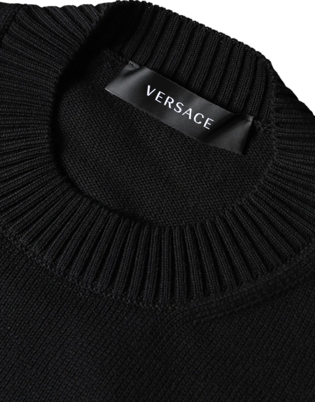 Pull à col rond Versace noir avec broderie Medusa, en coton, style élégant et sophistiqué, visible en détail dans l'image.