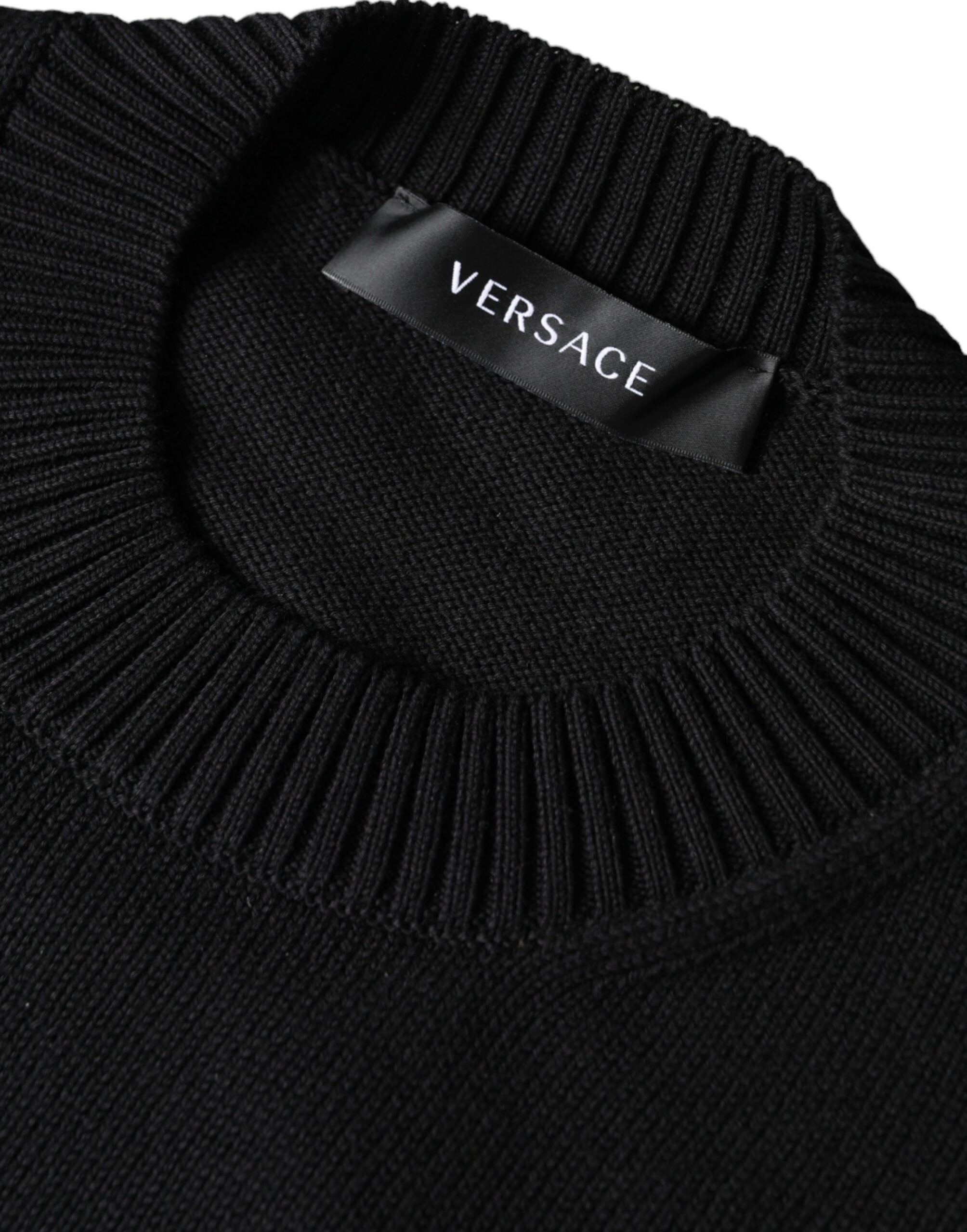 Pull à col rond Versace noir avec broderie Medusa, en coton, style élégant et sophistiqué, visible en détail dans l'image.
