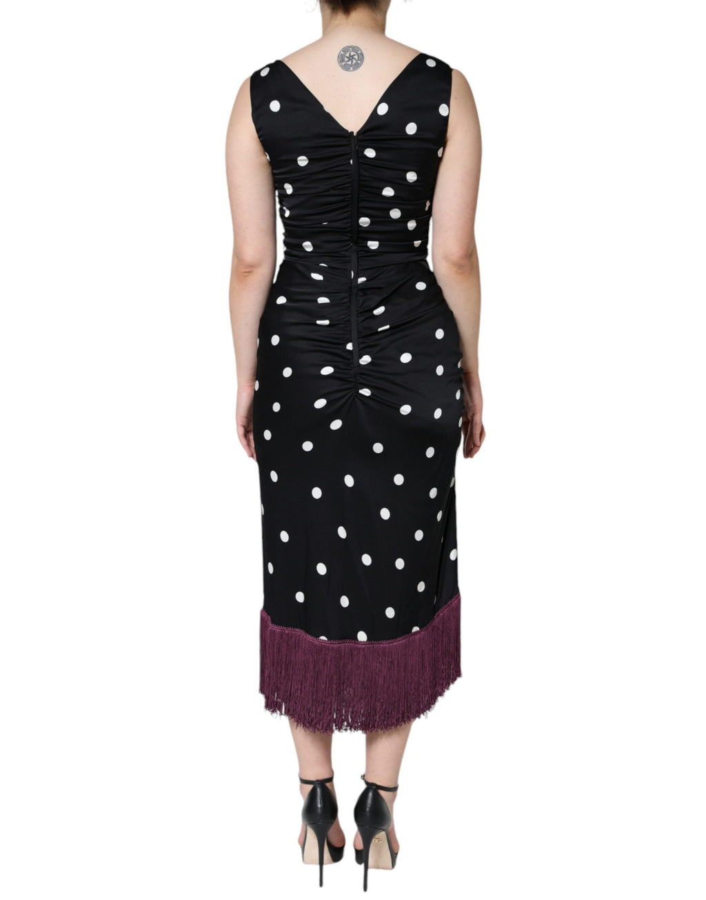 Robe midi en soie noire à pois, décolleté en V et franges, de la marque Dolce & Gabbana, portée élégante et sophistiquée.