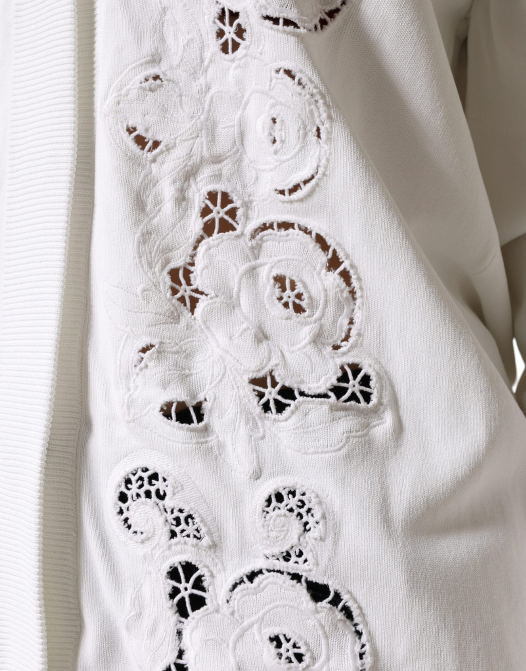 Cardigan Dolce & Gabbana en viscose blanche avec motifs floraux et découpes élégantes, porté ouvert sur un fond neutre.