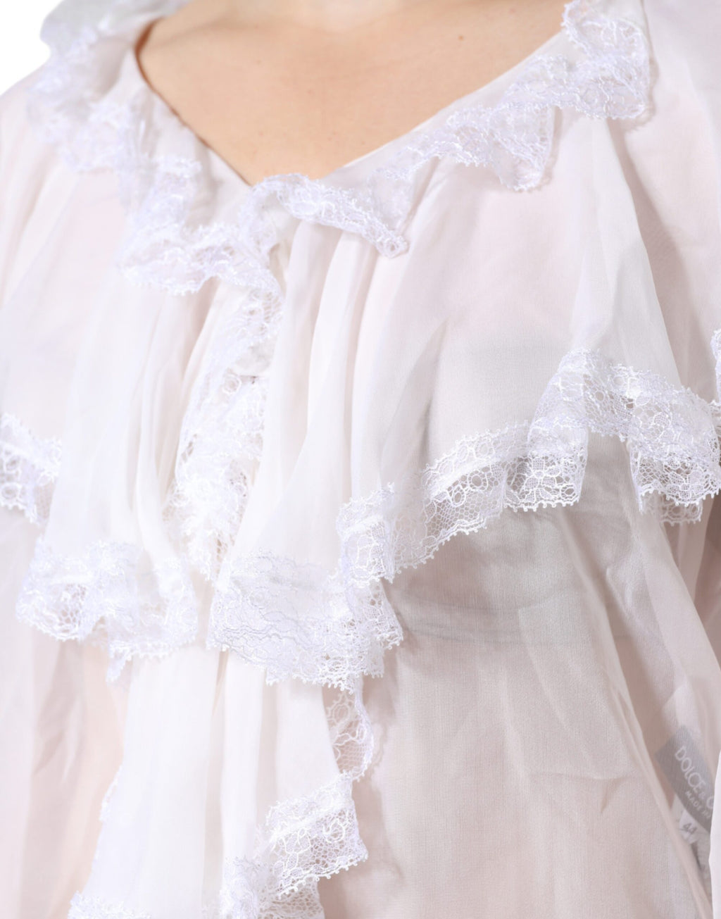 Blouse blanche à volants et dentelle à manches longues de Dolce & Gabbana, détails élégants et tissu délicat visible.