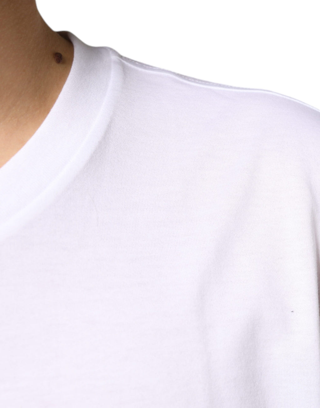 T-shirt blanc en coton Dolce & Gabbana avec logo en métal DG à manches courtes, visible sur l'image.