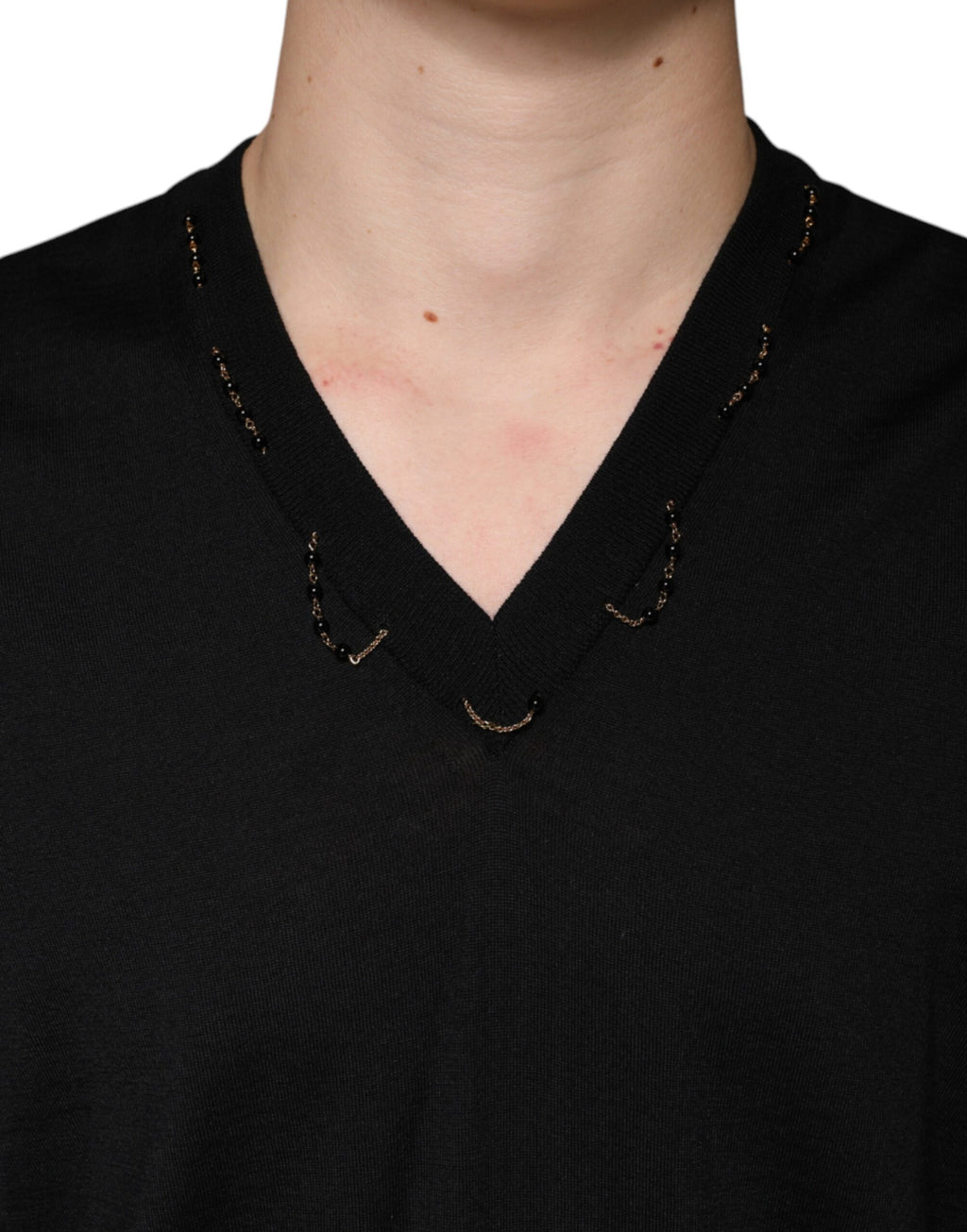 Pull noir Dolce & Gabbana en maille avec embellissements et col en V, porté de face.