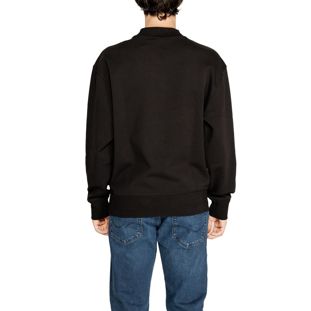 Sweat-shirt Calvin Klein Jeans noir en coton recyclé, avec logo discret sur la poitrine, porté dans un style décontracté.