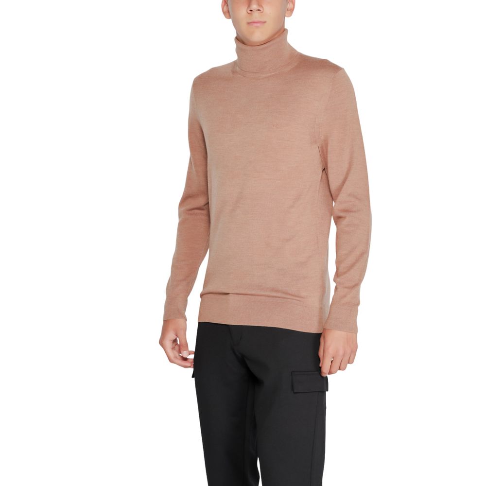 Pull en laine beige de Calvin Klein avec col roulé, doux et élégant, porté sur un mannequin.