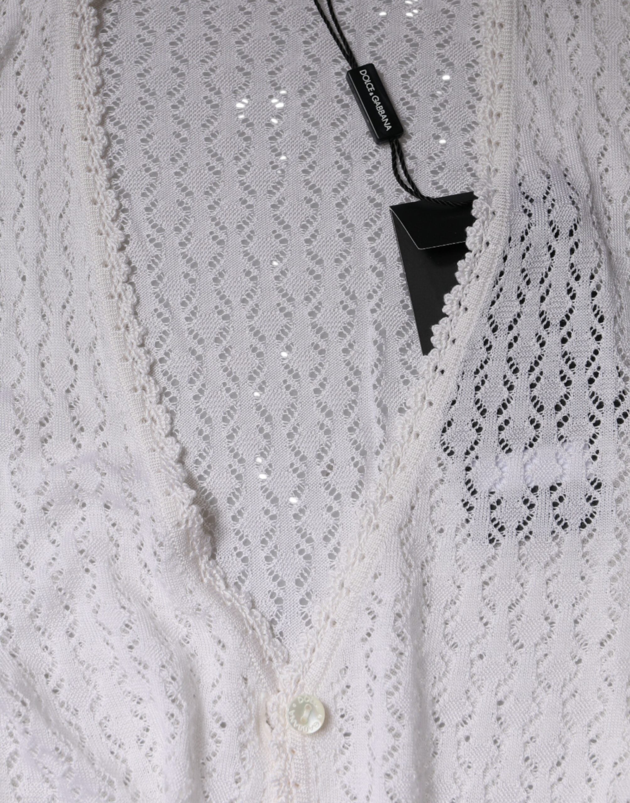 Cardigan blanc en soie Dolce & Gabbana avec boutons, porté sur un mannequin, détails élégants et tissu fluide visible.