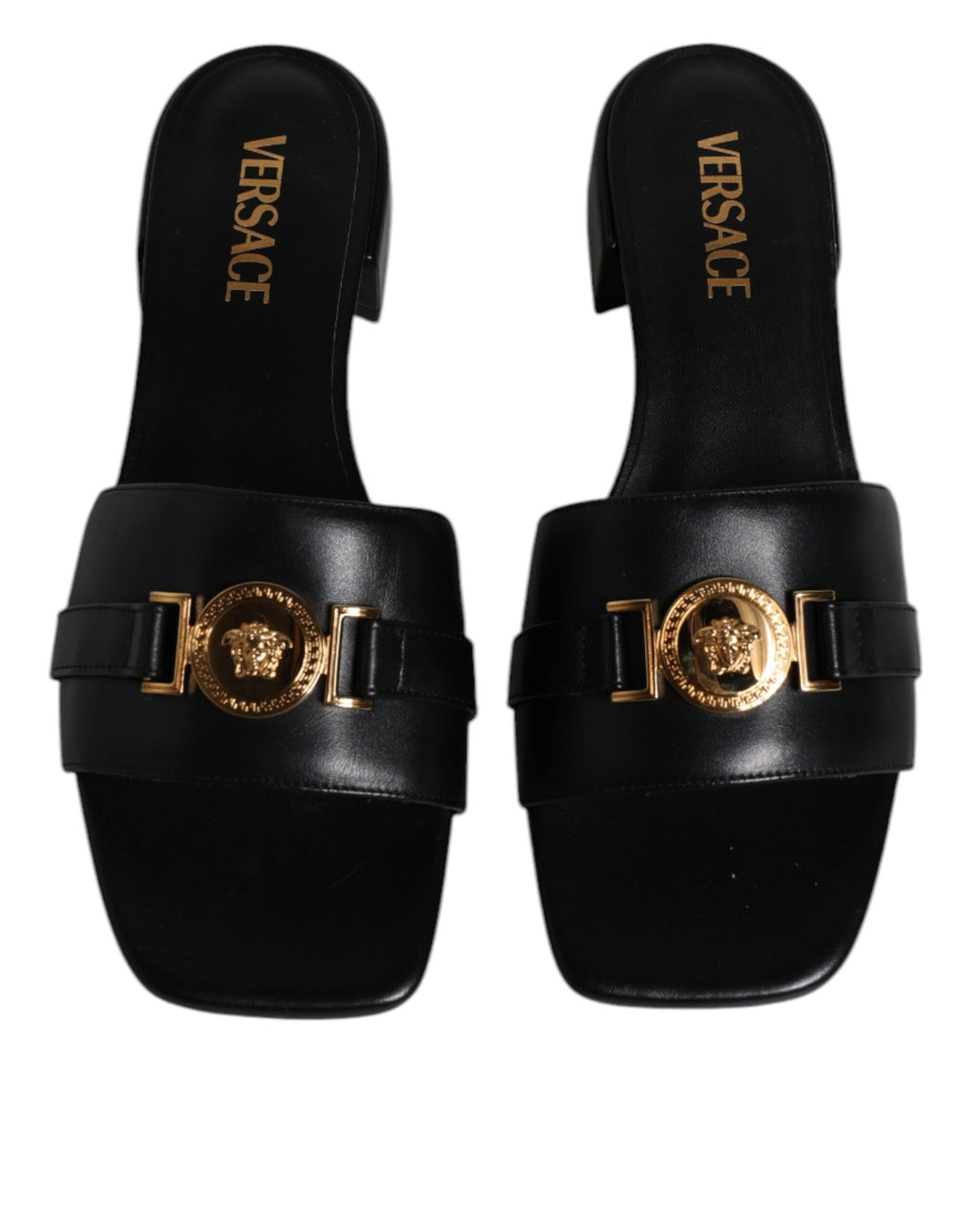 Chaussures plates Versace en cuir noir avec logo en plaque, slip-on, élégantes et confortables pour un style sophistiqué.