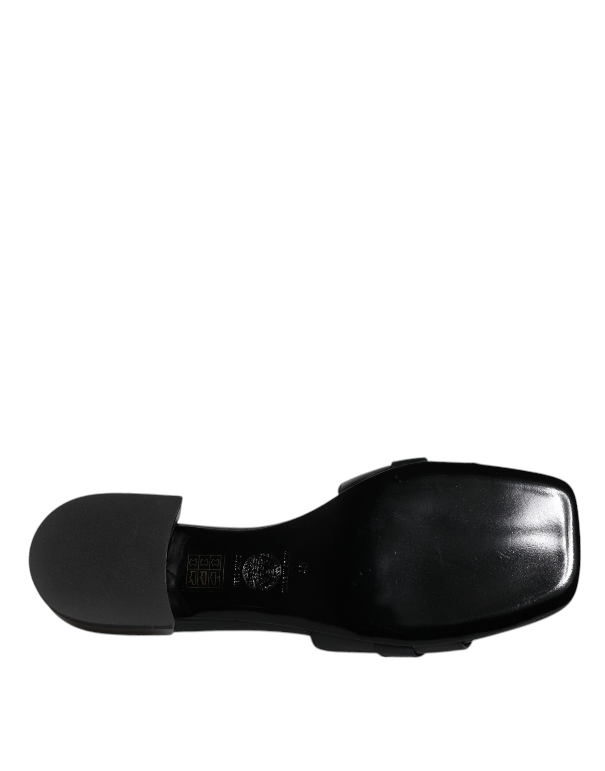 Chaussures plates slip-on Versace en cuir noir avec plaque logo élégante, confort et style pour un look sophistiqué.