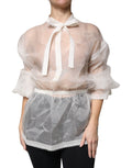 Blouse blanche à col ascot et manches longues de Dolce & Gabbana, élégante et raffinée, portée avec détails visibles.