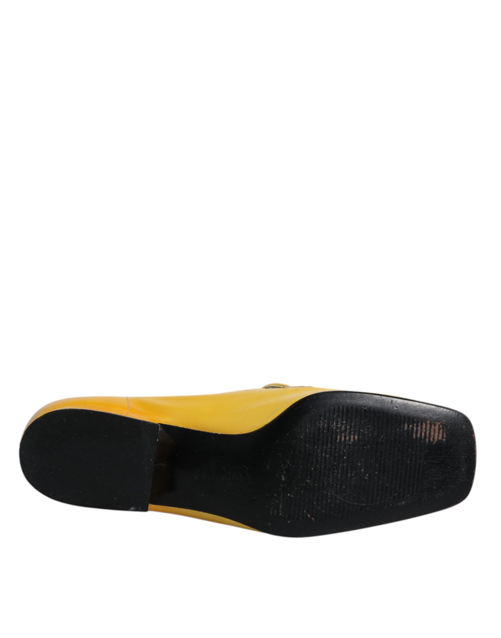 Mocassins slip-on en cuir jaune Dolce & Gabbana avec plaque logo élégante, pieds visibles sur fond neutre.