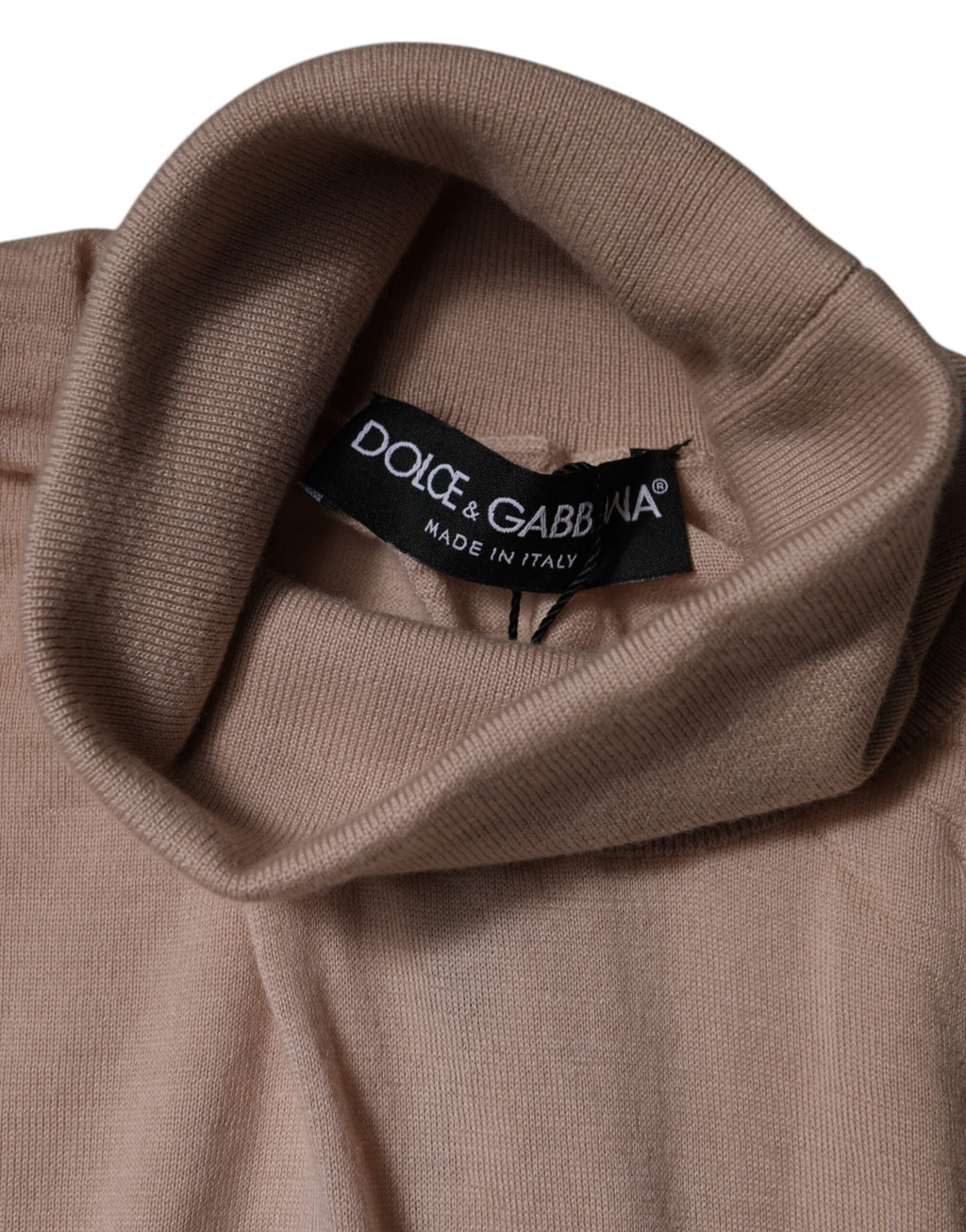 Pull-over beige en cachemire Dolce & Gabbana à col roulé, doux et élégant, porté sur un fond neutre.