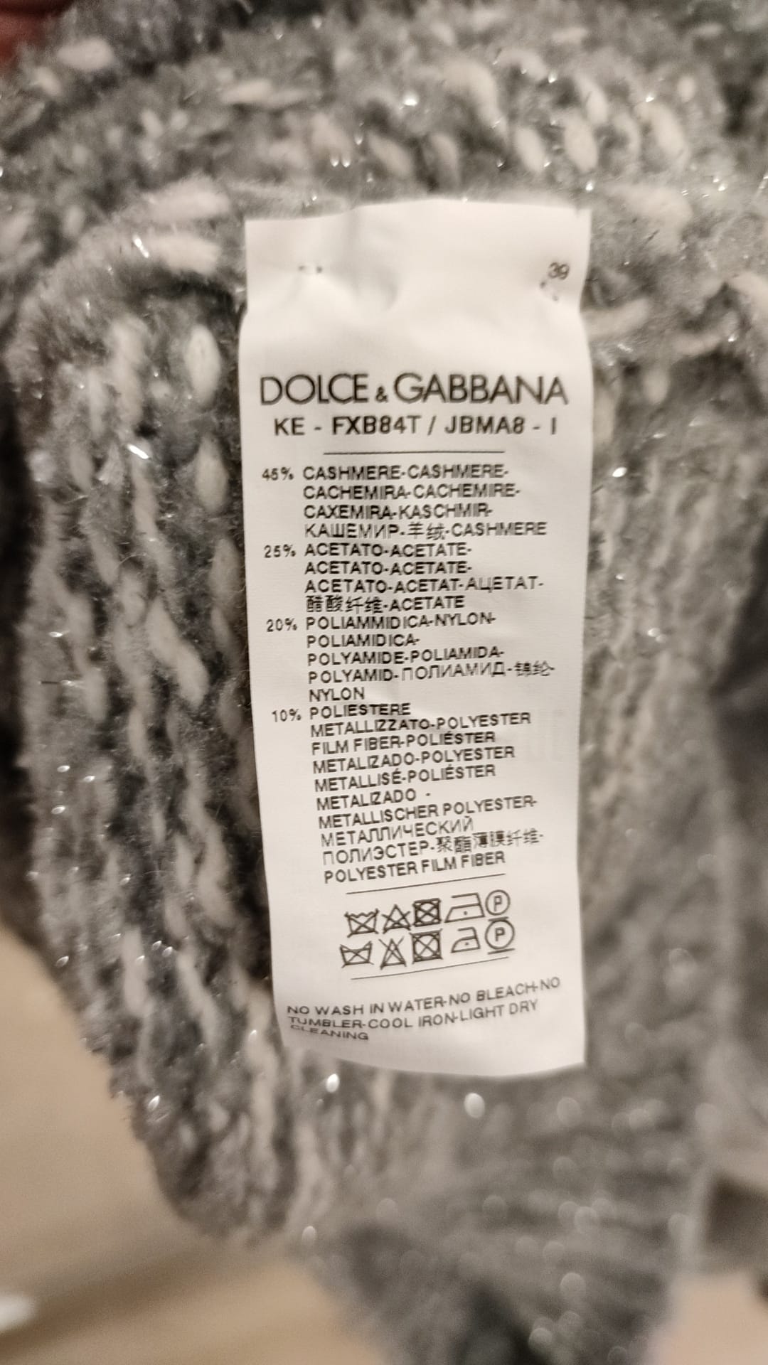 Pull-over en cachemire gris Dolce & Gabbana à col roulé, doux et élégant, porté sur un fond neutre.