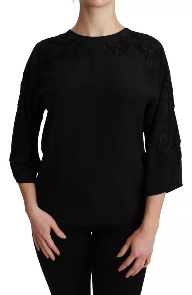 Blouse en soie noire Dolce & Gabbana avec broderie florale élégante et détails sophistiqués visible sur l’image.