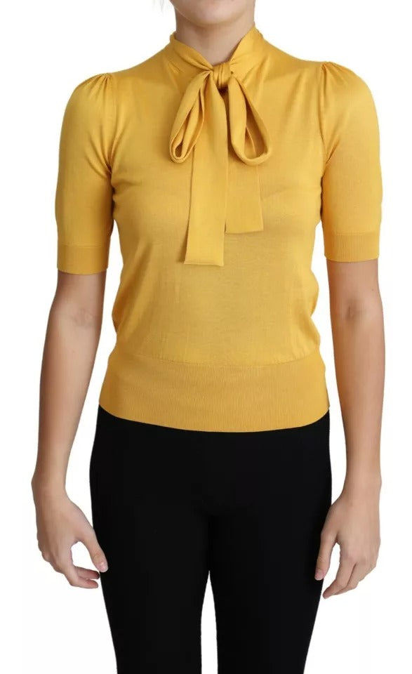 Pull-over en soie jaune Dolce & Gabbana avec col ascot, tissu tricoté élégant et détails raffinés visible sur l'image.