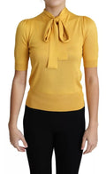 Pull-over en soie jaune Dolce & Gabbana avec col ascot, tissu tricoté élégant et détails raffinés visible sur l'image.