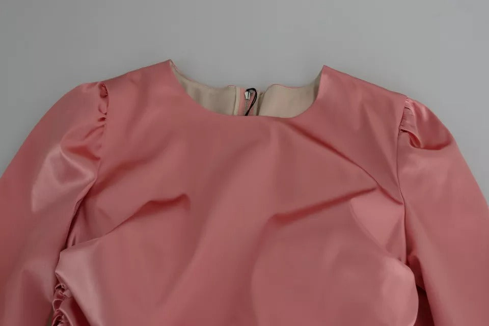 Robe midi Dolce & Gabbana rose à manches longues, silhouette ajustée et habillée, tissu élégant et féminin visible sur l'image.