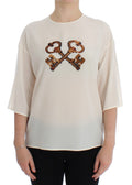 Haut en soie blanc Dolce & Gabbana avec sequins, style blouse ou T-shirt, détails élégants et finition raffinée.