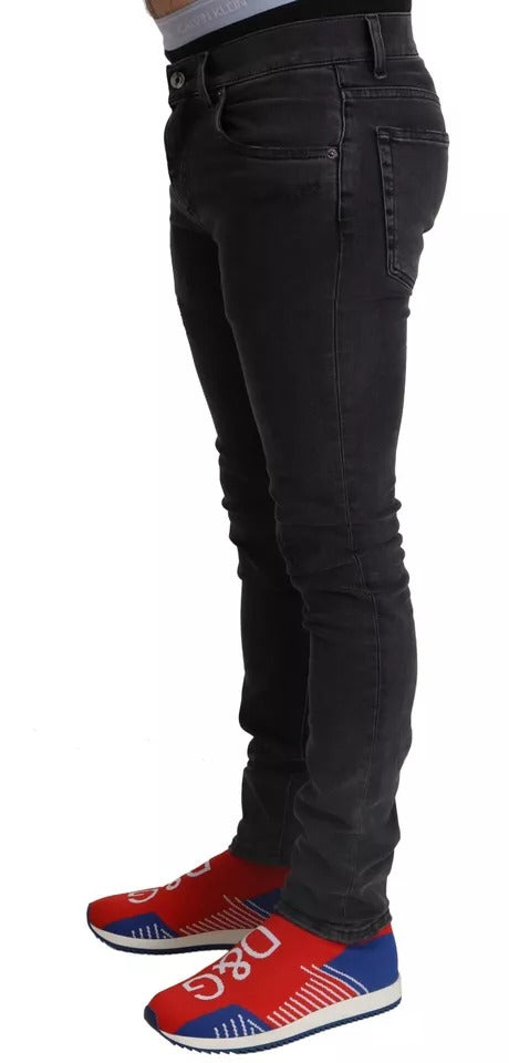 Jeans skinny en denim gris Dolce & Gabbana avec logo, coupe stretch et style décontracté, visibles sur l'image.