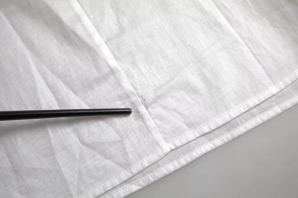 Blouse blanche en coton à dentelle avec col roulé de Dolce & Gabbana, détails élégants et finition raffinée visible sur l'image.
