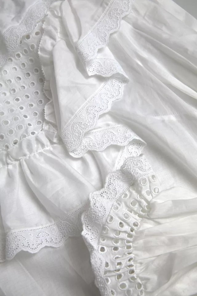 Chemisier blanc Dolce & Gabbana en coton avec bordure en dentelle et col roulé, détails élégants et finition raffinée.