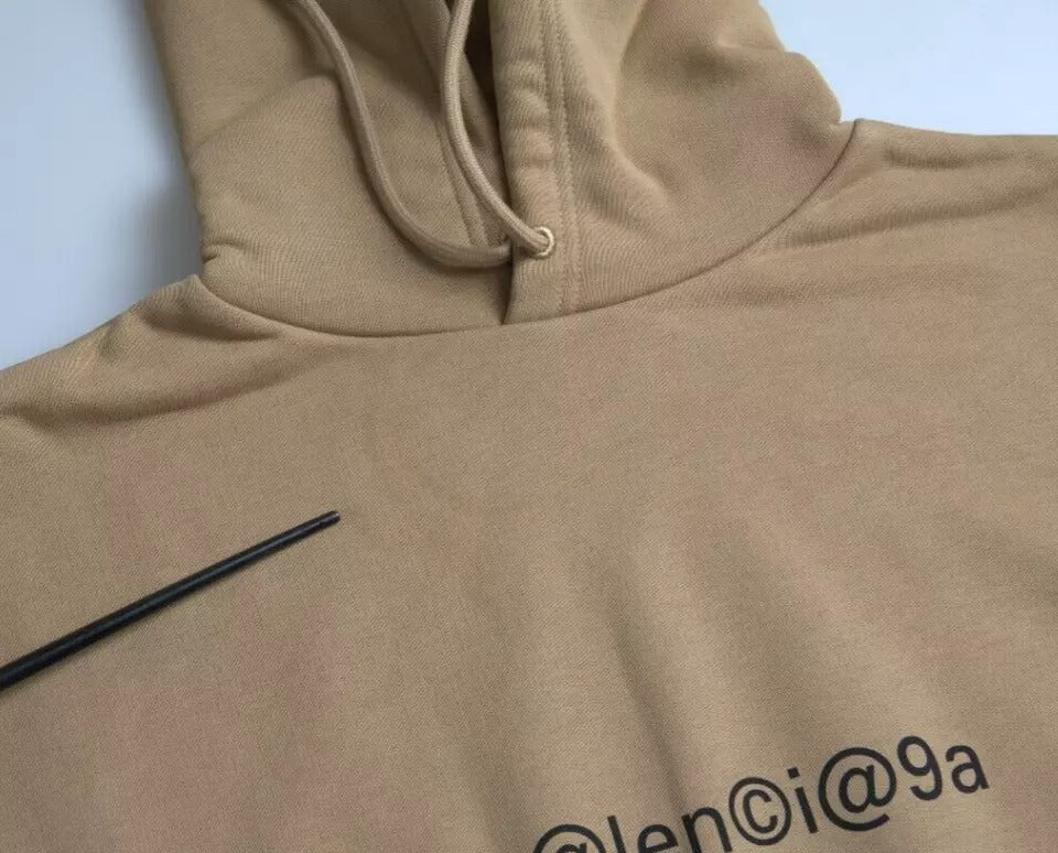 Sweat à capuche en molleton bouclette marron Balenciaga avec logo symbolique, doux et décontracté, porté sur un mannequin.