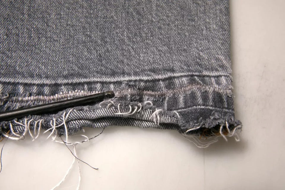 Jeans slim en coton stretch gris avec logo Dolce & Gabbana, denim skinny, visible sur l'image.