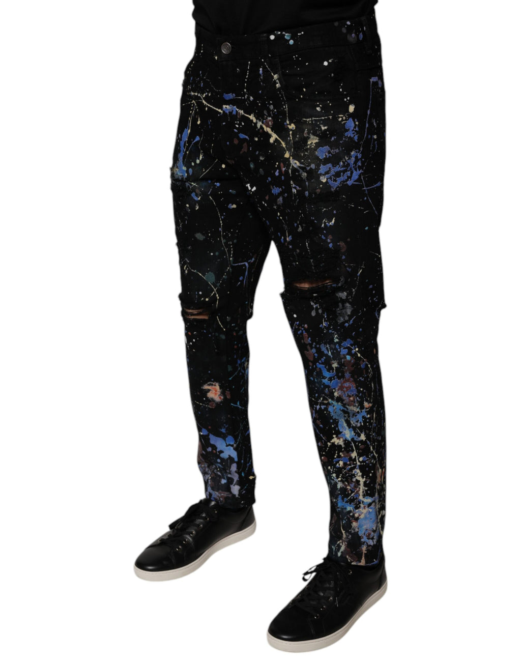 Jean skinny en denim coton noir avec éclaboussures de couleur, de la marque Dolce & Gabbana, visible en détail dans l'image.