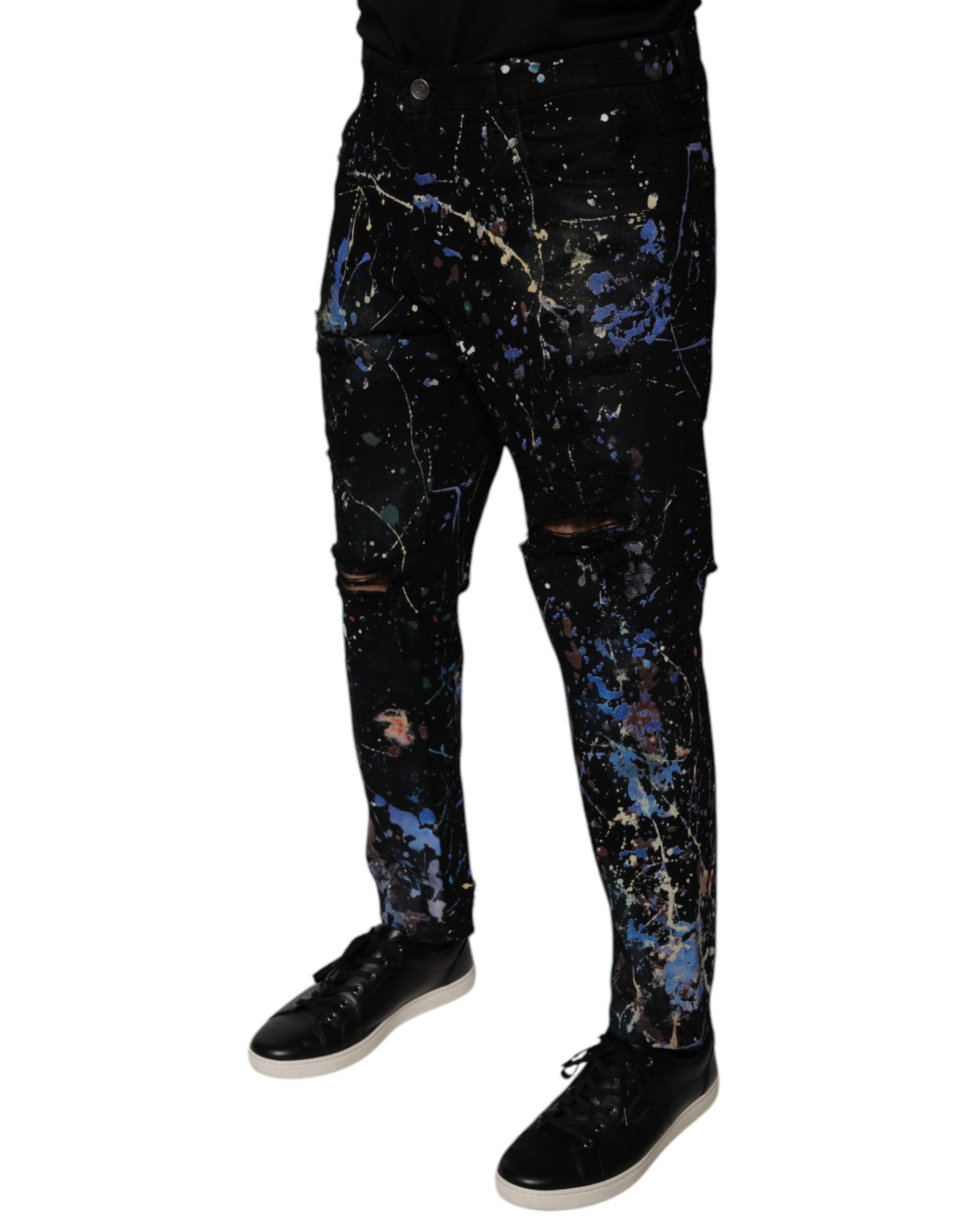 Jean skinny en denim coton noir avec éclaboussures de couleur, de la marque Dolce & Gabbana, visible en détail dans l'image.