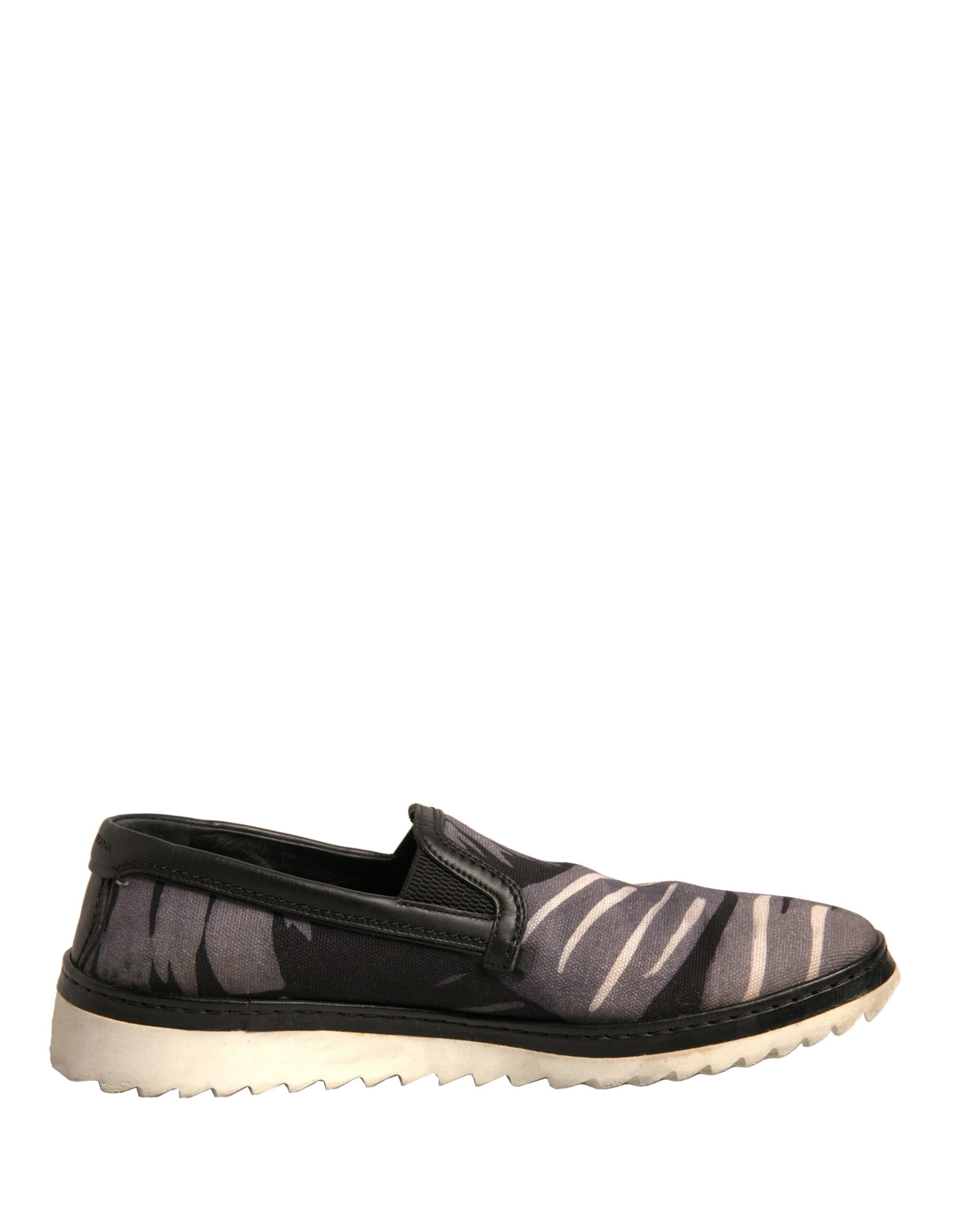 Chaussures slip-on Dolce & Gabbana en toile noire avec motif tropical, visibles en gros plan sur fond neutre.