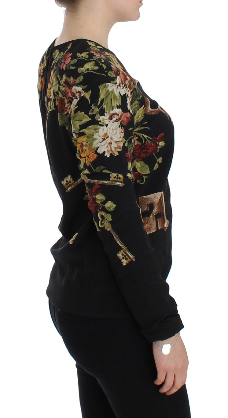 Blouse en soie noire Dolce & Gabbana avec motif floral clé, élégante et raffinée, portée sur un fond blanc.