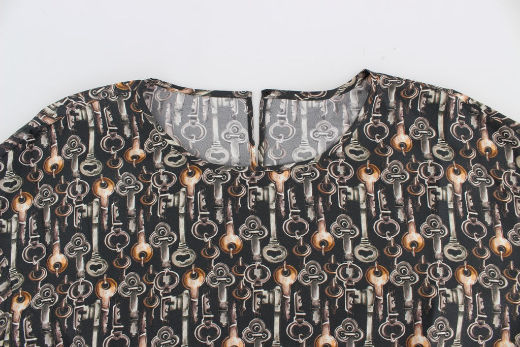 Chemise en soie Dolce & Gabbana gris or avec motif clé, style blouse ou t-shirt élégant, visible en gros plan.